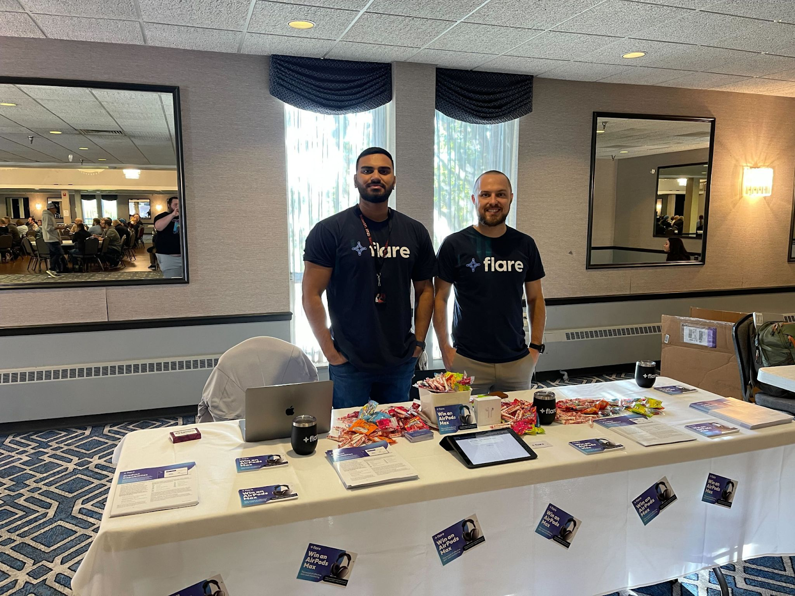 Flare Account Executive Nabil Shahid and Technology Partnerships Manager Jean-Christophe Taillandier stand behind a table with Flare flyers and candy.
